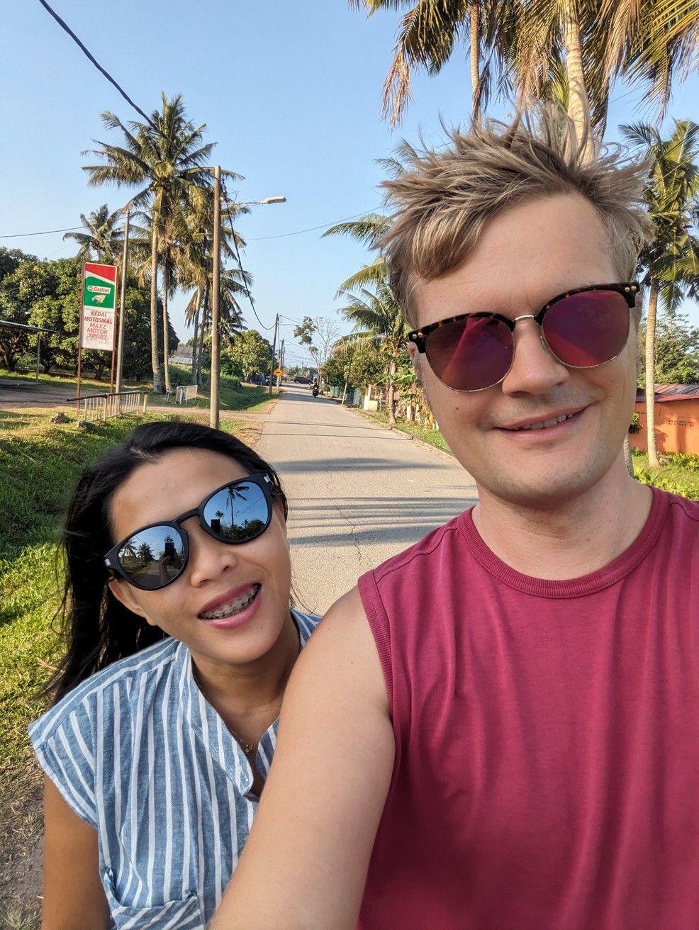 Lan und Martin, die Gastgeber von EasyLife, lächeln auf einer von Palmen gesäumten Straße in Hoi An