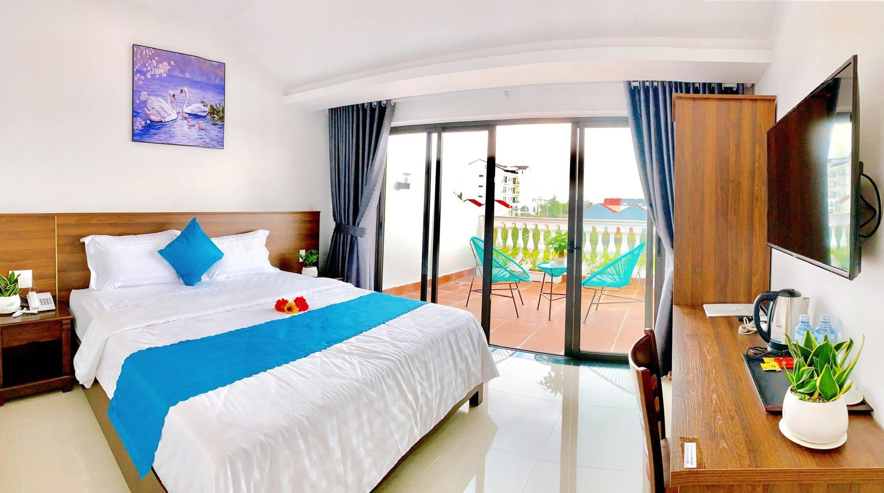 Helles Doppelzimmer in der EasyLife Villa mit blauem Bettläufer und Balkontür