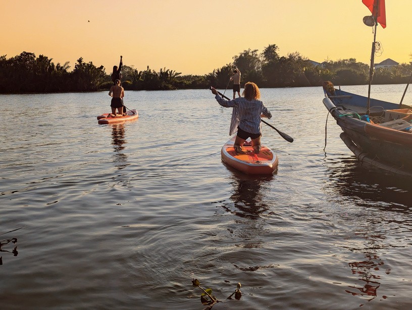Kind paddelt auf einem SUP-Board auf dem Fluss