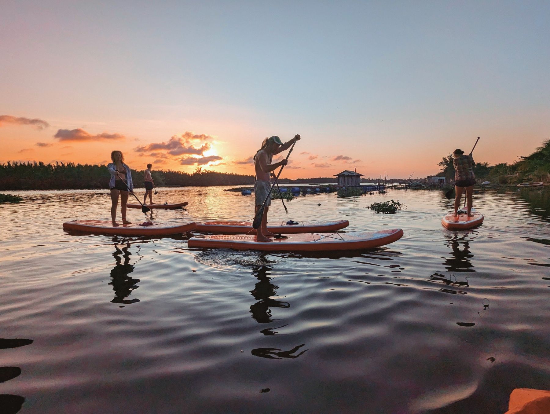 Stand-up-Paddler bei Sonnenuntergang auf dem Fluss bei Hoi An
